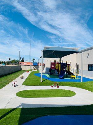 Preschool playground has two play structures and a tricycle path.