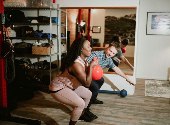 Physical Therapist helping someone squat with a kettle bell