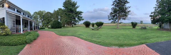 Backyard with a hammock, fire pit, and string lights facing farmland.