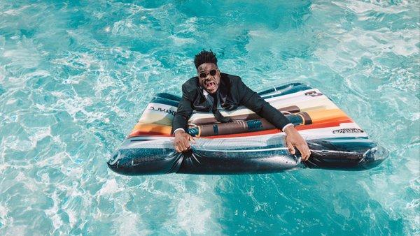 Florida Wedding DJ portrait featuring Malike Adigun of Curate Entertainment floating in a pool on a cassette tape floatie