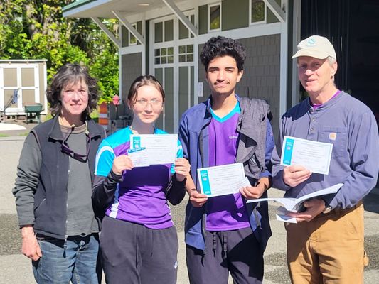 The coaches stand with two high school rowers who've just received their water safety certifications