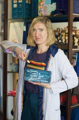 Katie Haynes in Thirteenth Doctor cosplay, holding a brick that says 'Be strong, even if it breaks your heart.