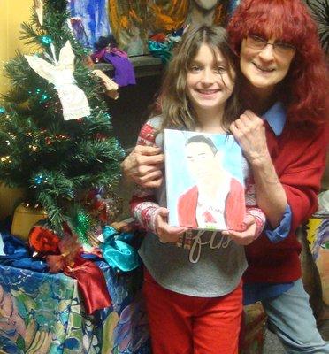 Joy Hellman with a student holding a photo of the painting that she did of her dad  under the angel tree