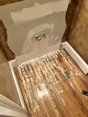 Hardwood floor and wall damage from a sink leak being repaired.