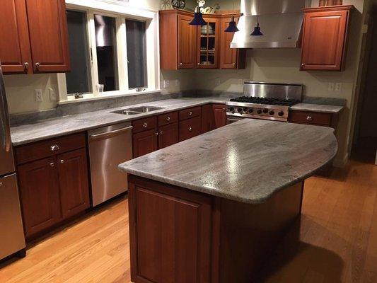 These counters are Brown Fantasy granite with a leathered finish. The radius on the island adds great character to the whole kitchen!