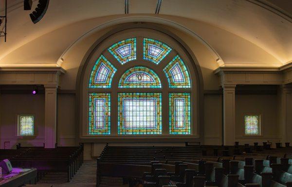 Stained glass window and pews in the Great Hall space.