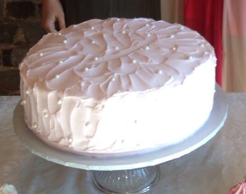 White almond cake with light pink icing and decorative edible pearls. It was delicious!