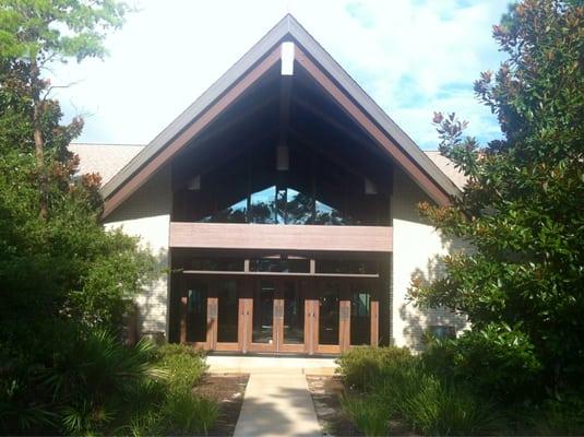 Warm, inviting, simple entrance, leading to a circular, contemporary church setting. Windows make up the walls. Still spiritual.