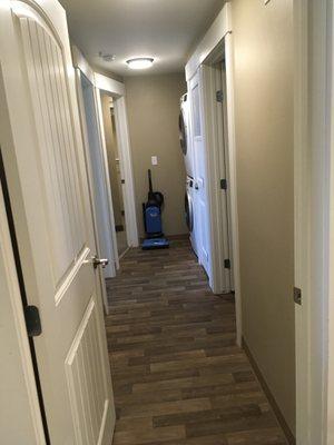 Hallway with washer, dryer, vacuum, iron, and ironing board.