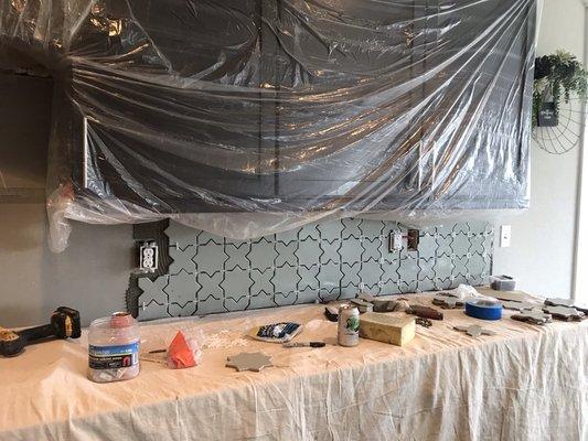 Star and cross hand made tile backsplash installed above upper cabinets gives a feeling like the entire wall is tiled.