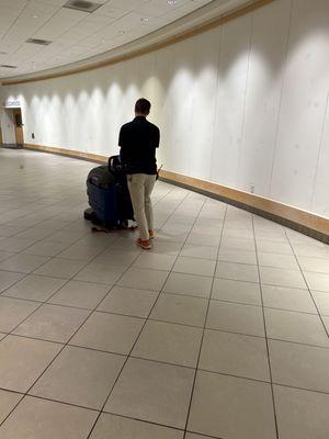 Cleaning tech uses an autoscrubber to clean the floors of a museum