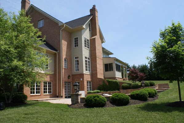 Terraced landscaping and stairs connect the lower level patio to the rear covered and screen porches off the kitchen...