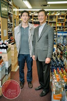 father & son in a sea of wine bottles