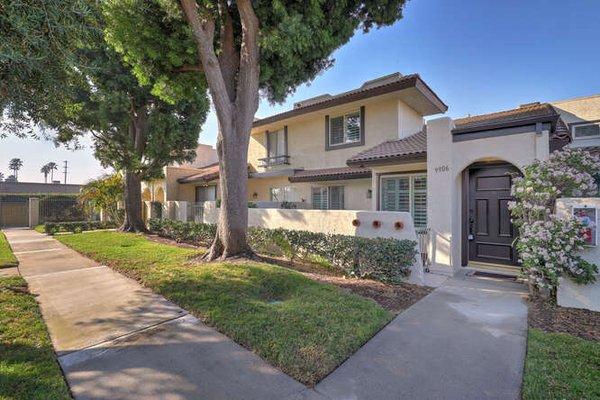 Charming townhouse with lush landscaping, mature trees, and a well-kept exterior.