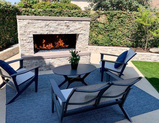 Outdoor fireplace with seating and artificial grass