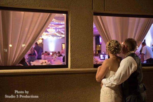 Wedding couple looking in their own reception. Love this picture!