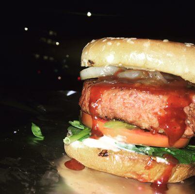 Supreme burger, toasted bun, caramelized grilled onions, avocado, tomatoes, pickles, veganaise, vegan cheese, and barbecue Sriracha.