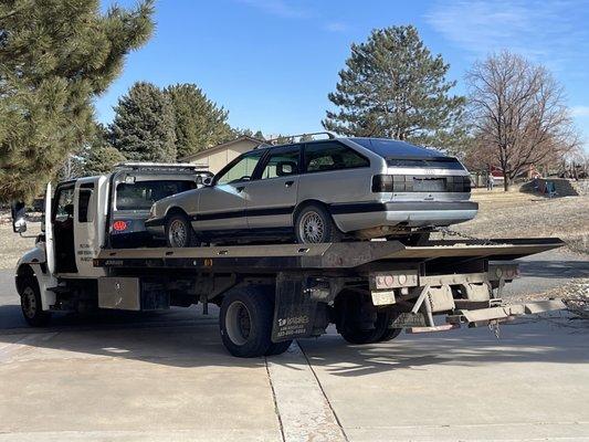 A tow truck towing a vintage Audi.