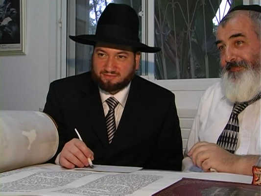 Rabbi Yitzchak Kimmel writing a letter into a Sefer Torah