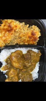 Delicious and juicy curry chicken with white rice and a side of cheesy baked Mac .