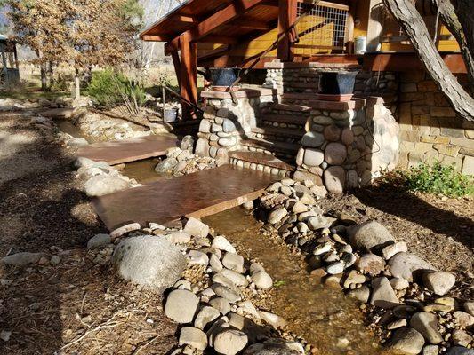 Water feature river, with stone bridge for access to front door.