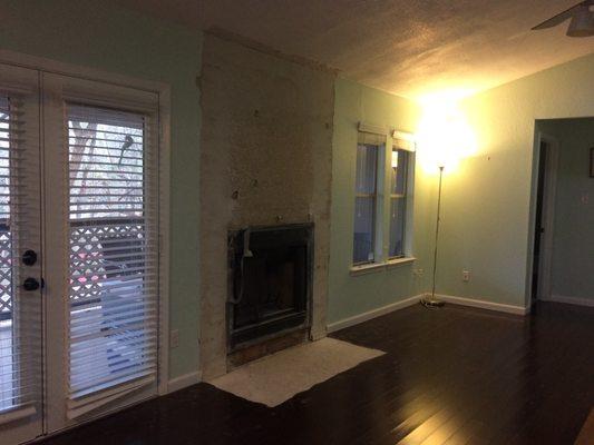 Before photo: French doors, fireplace (stones and hearth already removed), two tiny windows