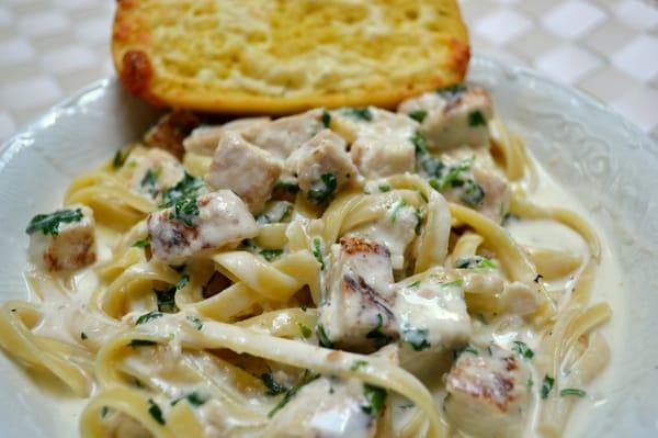 Chicken Alfredo served over fettuccine pasta with garlic bread.