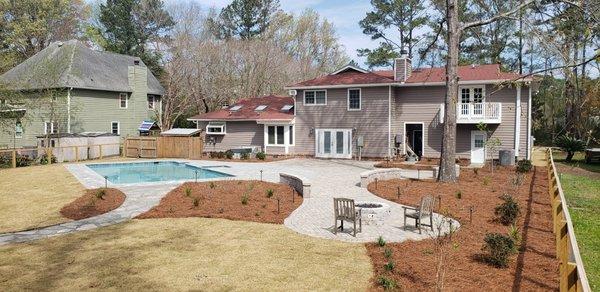 Pool patio and outdoor living space accented with a beautiful lawn and plantings.