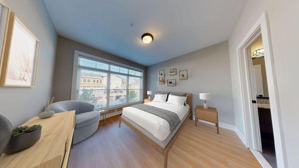 A bedroom with hardwood-style flooring and a large window at The Lofts at Saratoga Blvd.