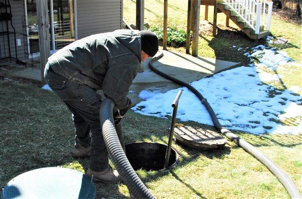 Service technician vacuum cleaning a septic tank.