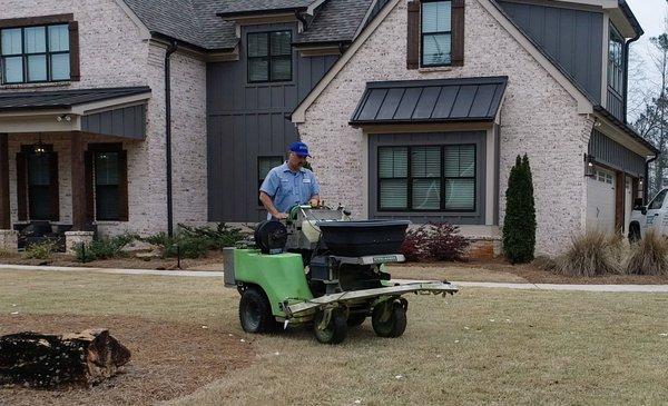 Turf Magic employee applying weed control with one of our ride-on spray units.