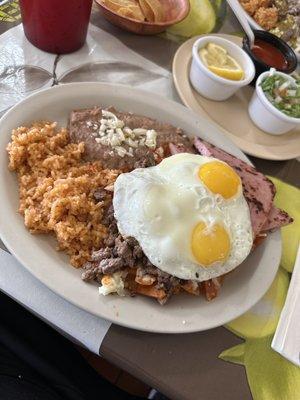 Chilaquiles with carne asada piece of ham & sunny side up eggs