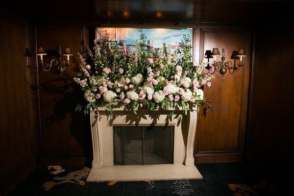 Fireplace mantle floral arrangement designed by Laura, Poppy's Petalworks, to hide a very unattractive picture over the fireplace