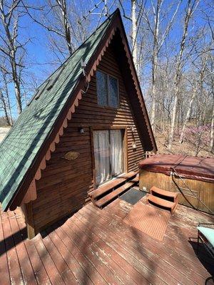 A-frame Cabin 6 back deck with hot tub, furniture and view of the woods.