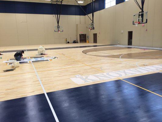 Installing logos on gym floor at Knoxville High School