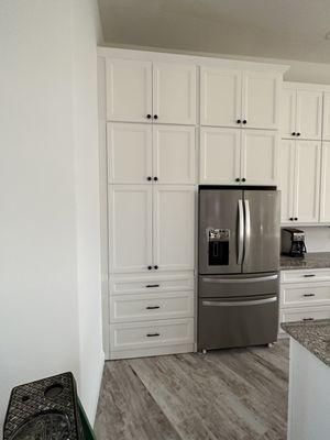 There is a door left of fridge that goes into pantry.