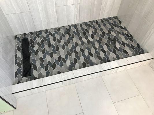 Leaf mosaic tile custom shower pan is a unique highlight of this bathroom / shower remodel.