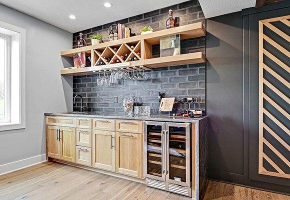 Custom wine storage, integrated stemware rack, quartzite waterfall countertop, engineered hardwood flooring.