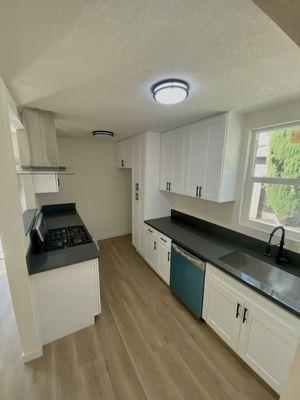 A beautiful white shaker cabinet Kitchen with an elegant black countertop. Topped with a oven-hood, pull-down faucet and undermount sink.