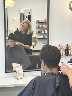 Demetrios receiving hair cut from Lucinda.