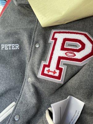 Letterman jacket with name embroidered on front and a patch attached.