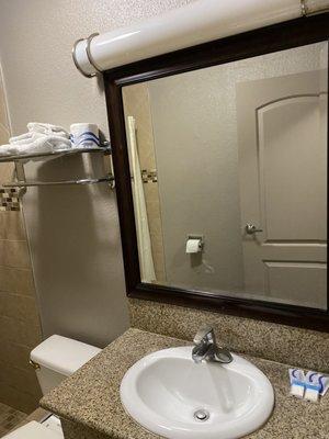 Bathroom sink stocked with supplies and towels