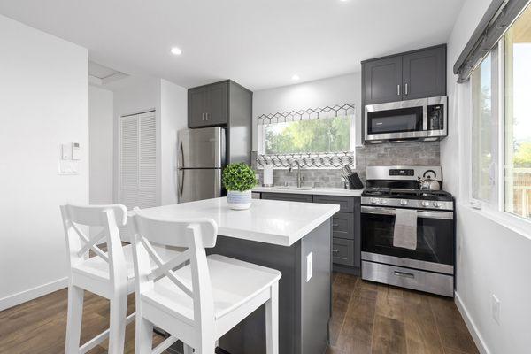 Complete Accessory Dwelling Unit build. Kitchen area w/center island. Also, stacked Washer & Dryer combo hidden behind white folding doors.