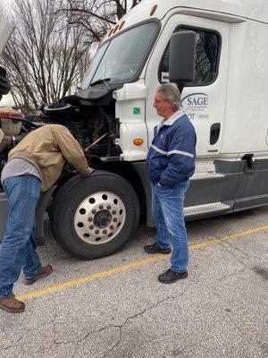 Sage instructor assisting student in identifying vehicle front end components.