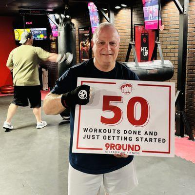 Member "Hands On" Ron proudly poses with the brag board after finishing his 50th session at 9ROUND Kickboxing Fitness in Fairlawn, Ohio