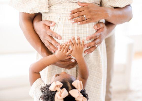 Toddler and couple touching pregnant belly.