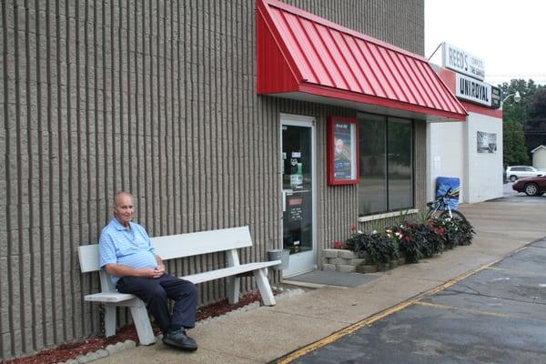 Owner Chet Reed sits proudly in front of Reed's Tire.  At 75, Chet stills works everyday.