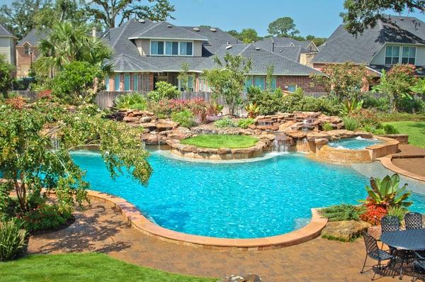 Large pool design complete with grass terrace, cascading spa, and waterfall.