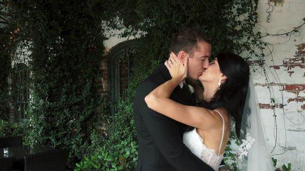 Jennie and Taylor sharing in a moment outside Melrose Knitting Mill on their wedding day in Raleigh