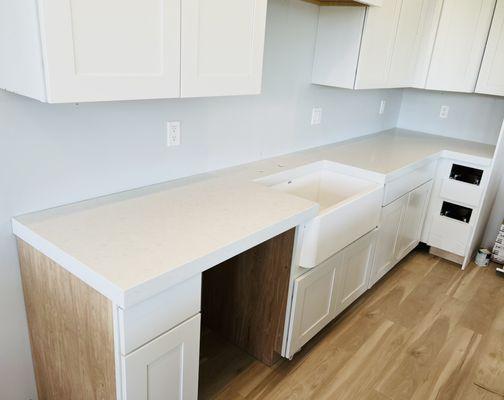 White quartz featuring a beautiful white farmhouse sink as well as a laminated edge!